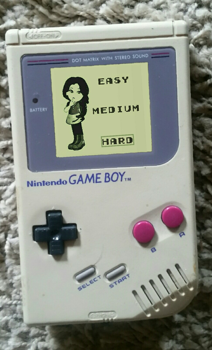 Photograph of an original gameboy, with cartoon depiction of woman next to the word easy, medium, hard. Hard is highlighted 