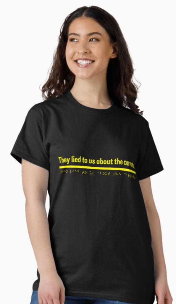 Woman with dark hair wears a black t-shirt with the words in yellow. They lied to us about the carrots. Braille font underneath reads same.