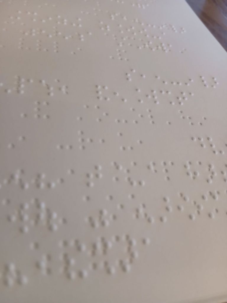 A close up photograph of a white page with Braille text